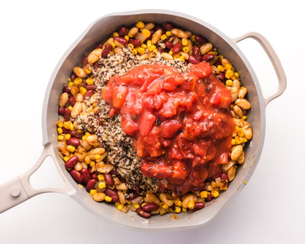 Tomates have been added to a skillet with other ingredients.