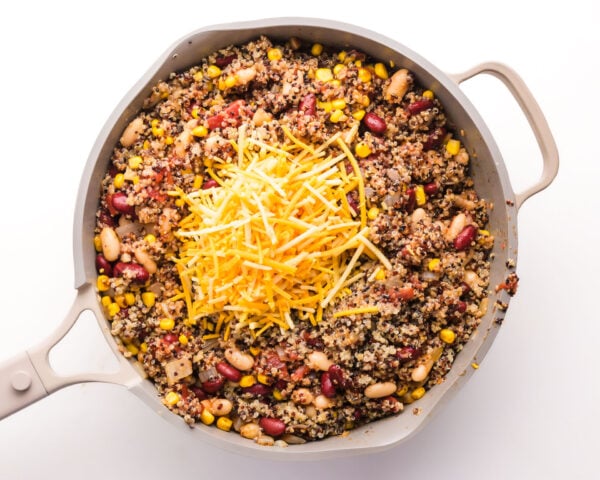 Cheese has been added to a skillet with a quinoa and bean mixture.
