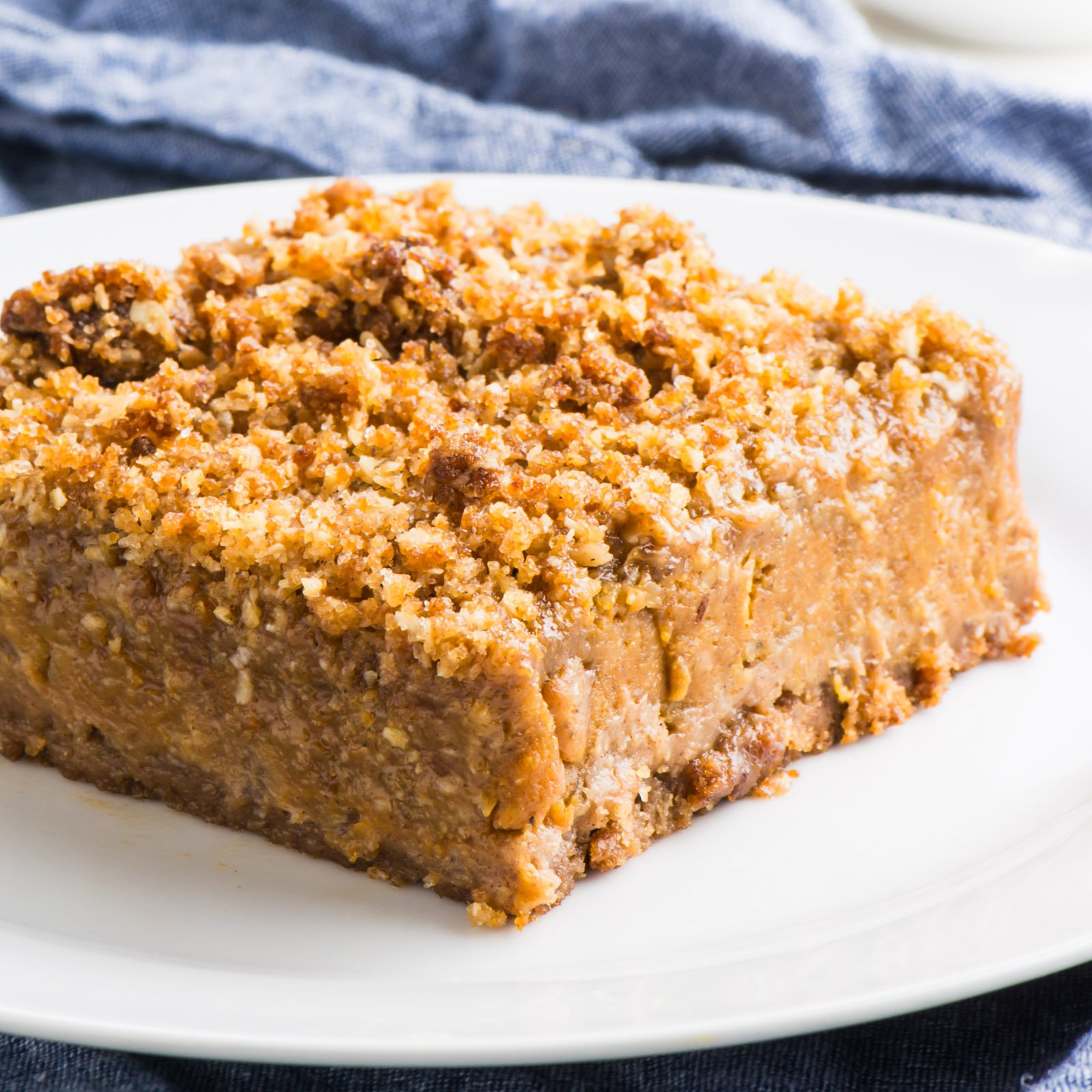 A Vegan Pumpkin Bar sits on a plate on a blue kitchen towel.