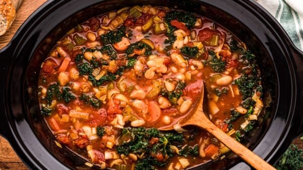 looking down into a slow cooker with soup and a ladle.