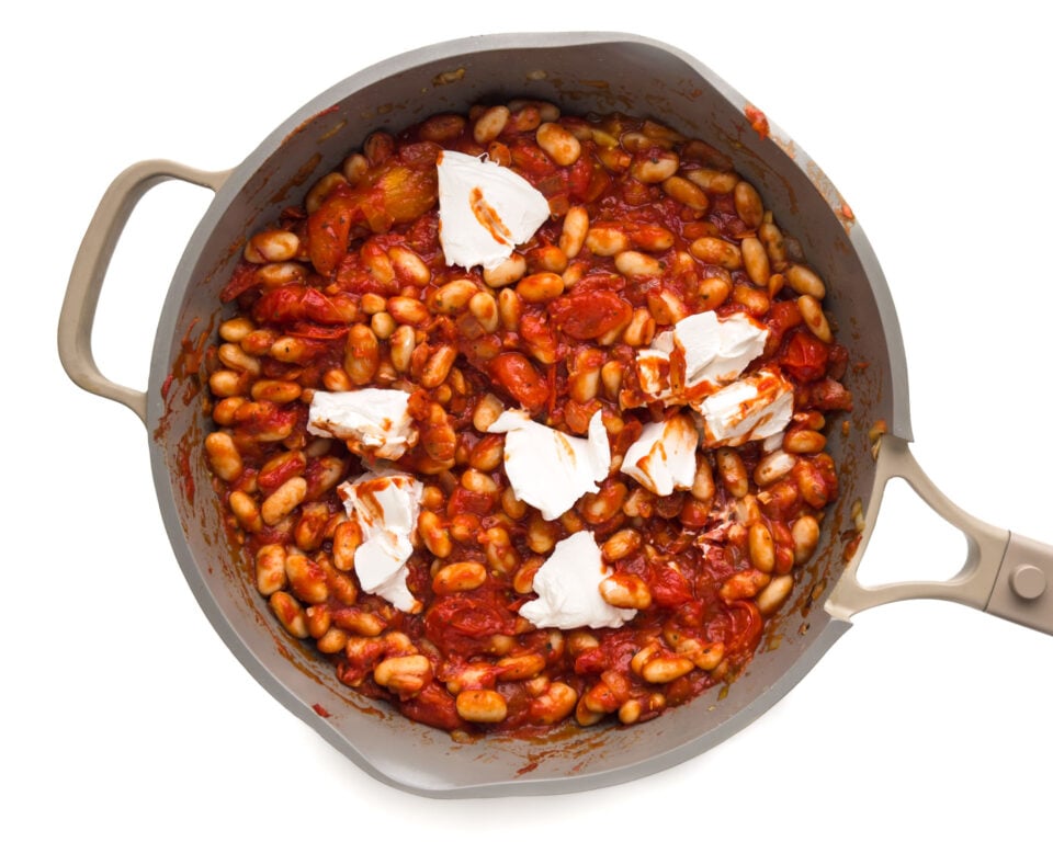 Vegan cream cheese is added to skillet with a tomato sauce mixture.