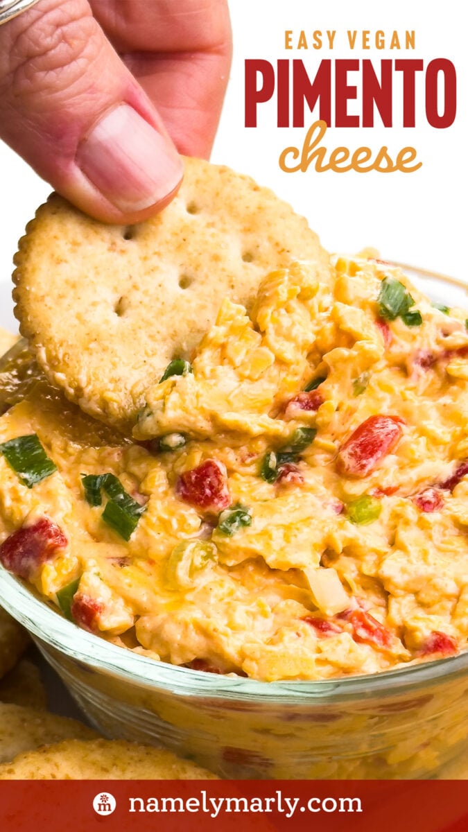 A hand uses a cracker to dip from a bowl of cheese dip. The text reads, Easy Vegan Pimento Cheese.