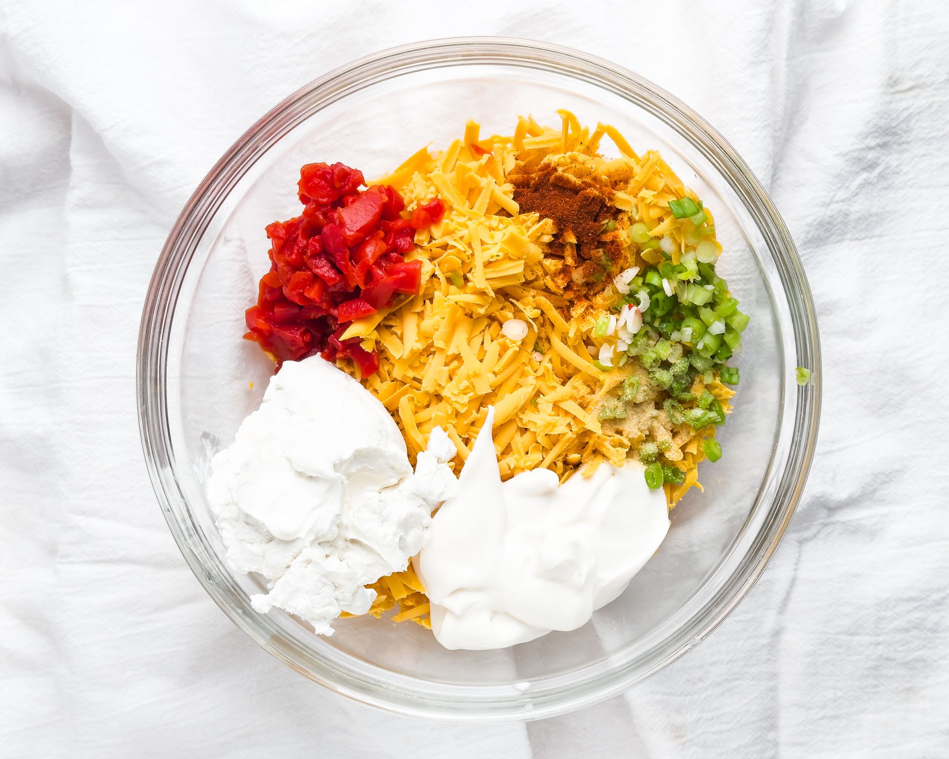 Ingredients like vegan cheese and pimentos are in a bowl.