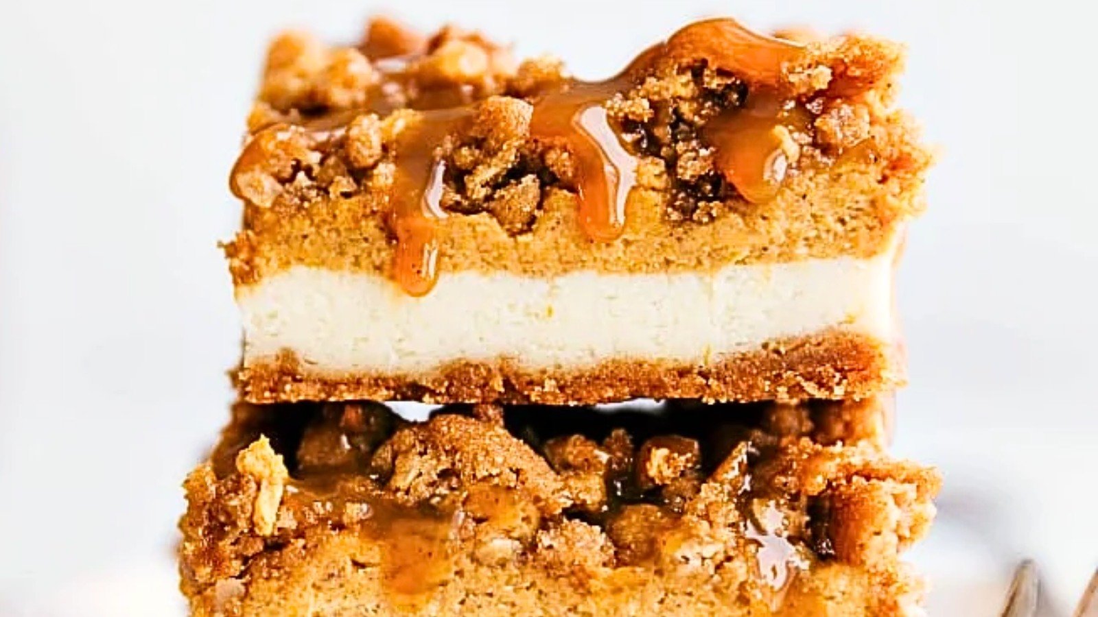 A stack of pumpkin cheesecake bars has caramel sauce coming over the edges.