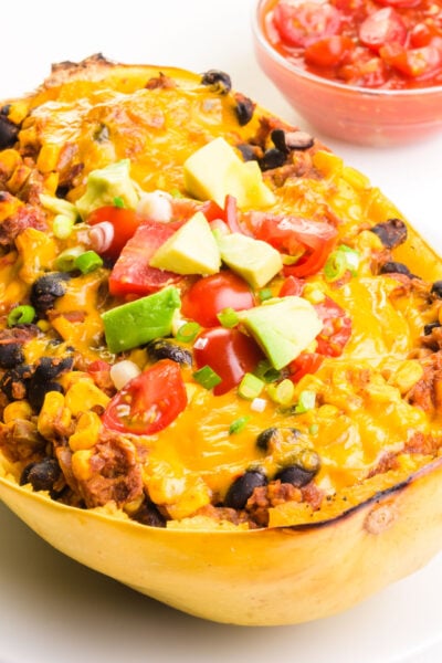 A baked spaghetti squash is filled with ingredients like black beans and melty vegan cheese.