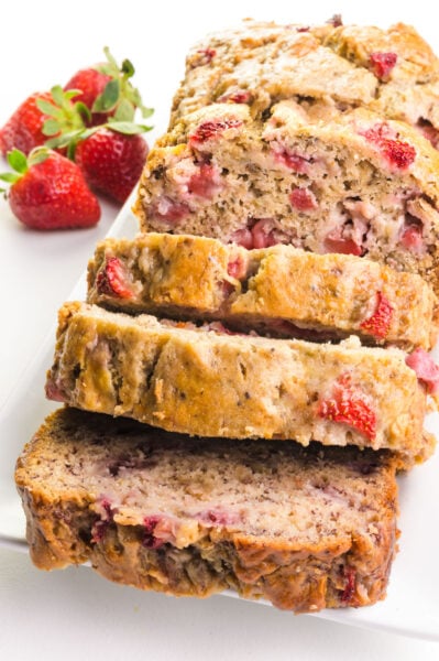 A loaf of strawberry banana bread has several slices cut out.