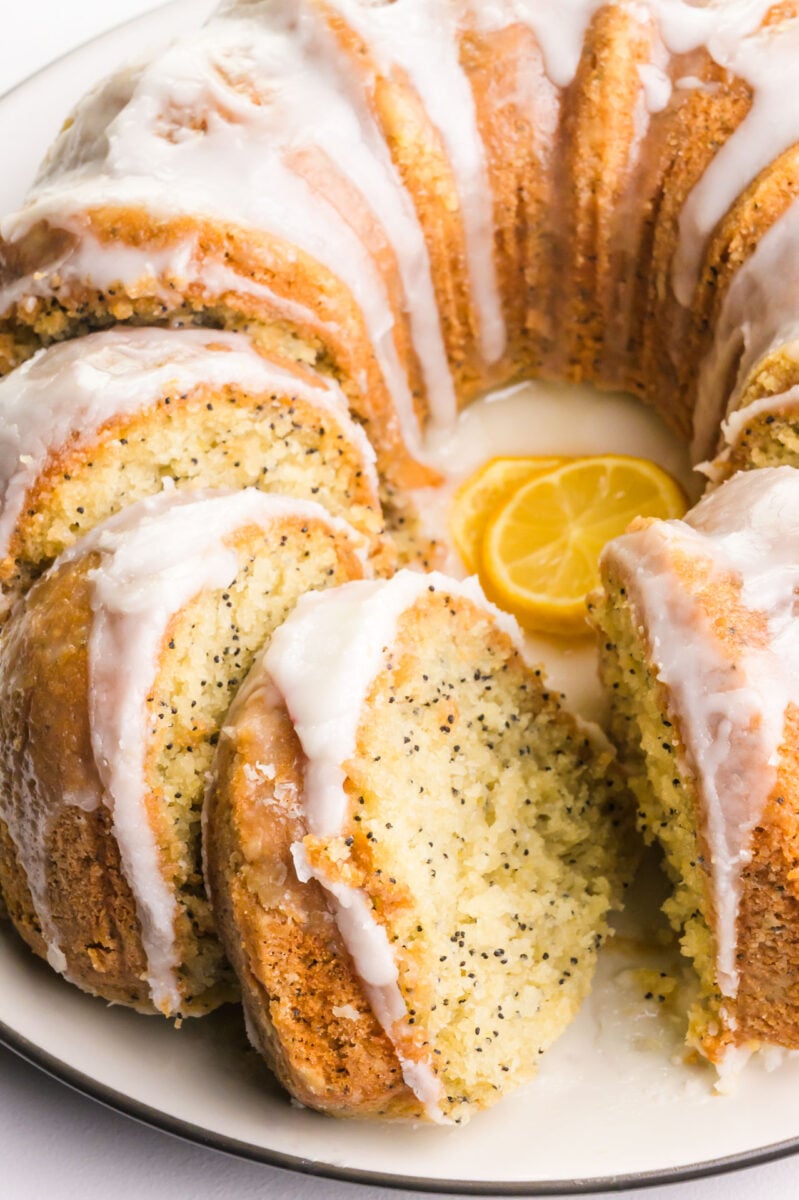 A lemon Bundt Cake has drizzles over the top and is cut into slices.