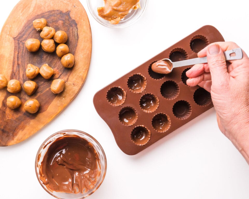 Melted chocolate is being spooned into a mini candy mold.