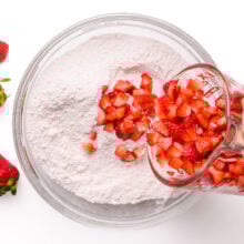 Fresh chopped strawberries are being poured into a flour mixture.