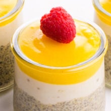 A closeup of lemon chia pudding in a glass serving jars with a raspberry on top.