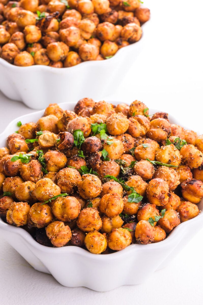 A bowl holds roasted chickpeas with herbs on top.