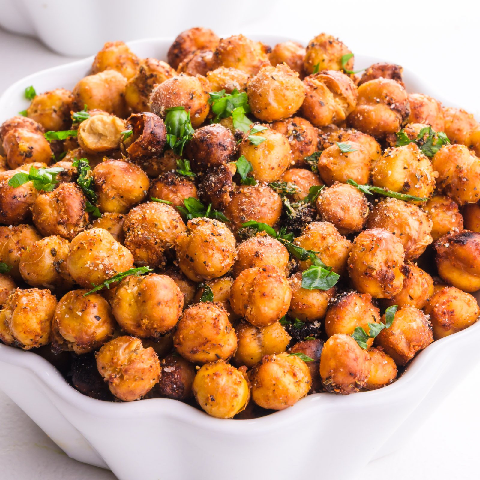 A bowl of mediterranean roasted chickpeas has herbs on top.