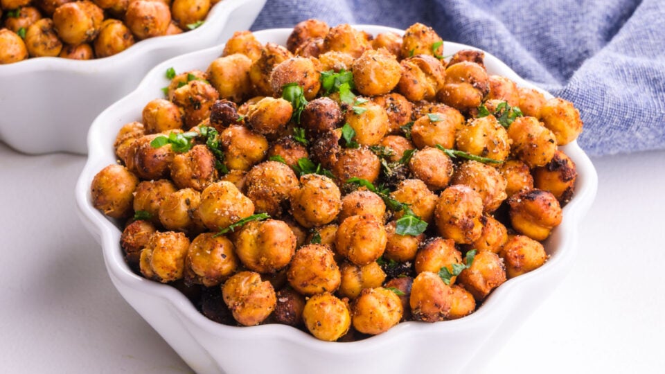 A bowl of mediterranean chickpeas has fresh herbs on top.