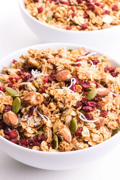 A white bowl holds coconut granola with dried fruit on top.
