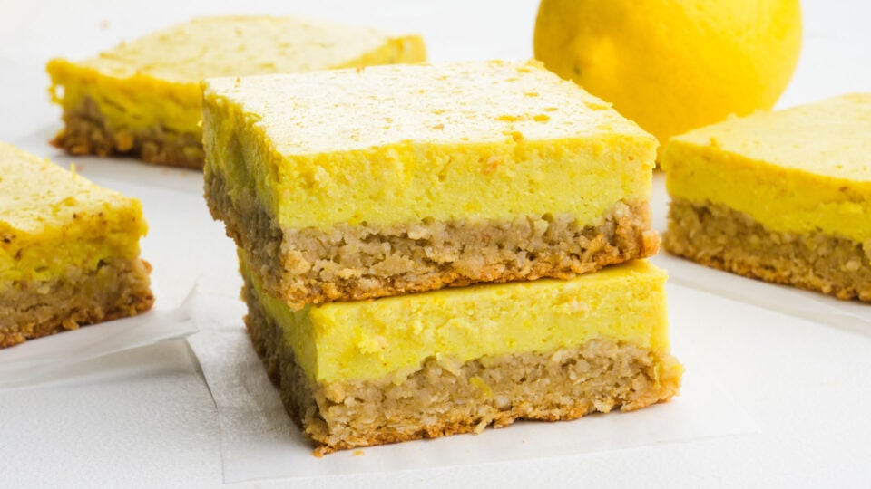 A stack of healthy lemon dessert bars with more of the bars sitting beside it.