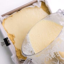 A creamy filling is being poured over a crust in a pan.