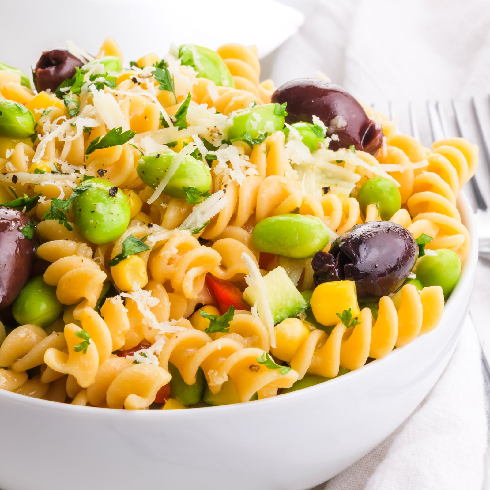 A closeup of pasta salad with tasty veggies on top.