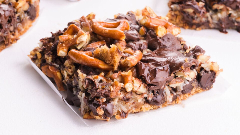 A slice of a layered magic dessert bar on a white table. 