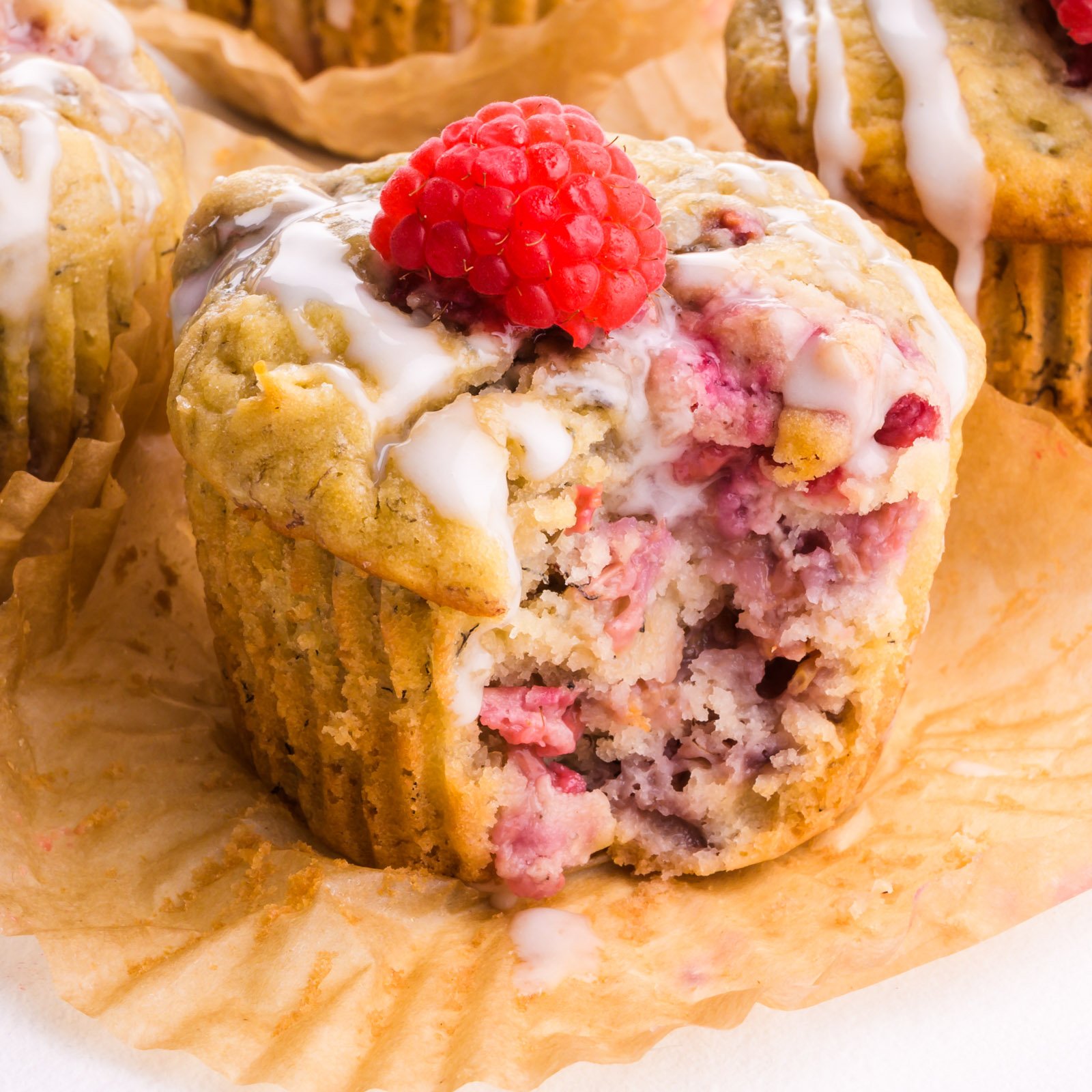 A raspberry banana muffin with a bite taken out sits in a muffin paper.