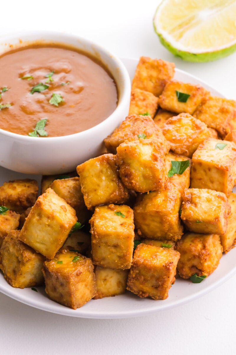 A plate of fried tofu sits near a bowl of dipping sauce.