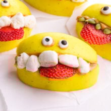 An apple monster halloween treat has candy eyes, marshmallow teeth, and a strawberry tongue.