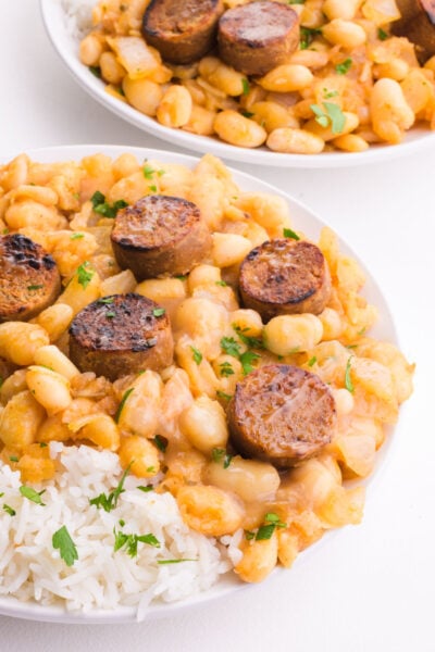 Two bowls of white beans and rice on a white table.