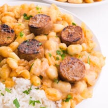 A closeup of white beans and rice in a bowl topped with veggie sausage.