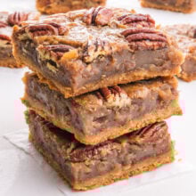 A stack of pecan pie bars with more in the background.