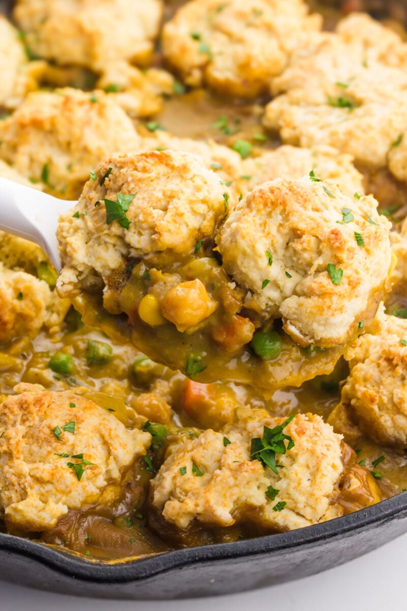 A serving of chickpea pot pie hovers over the rest of the pie in a skillet.