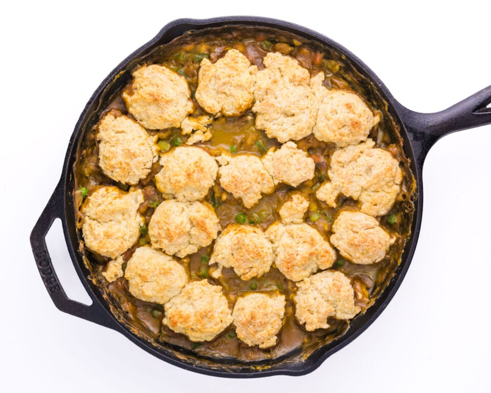 A baked biscuit pot pie is in a cast iron skillet.