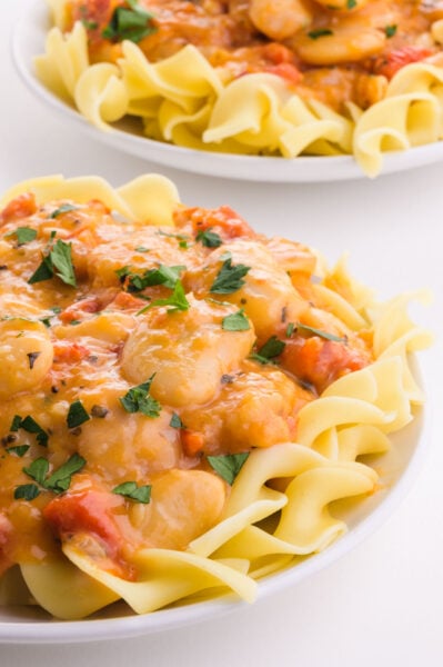 Two plates of Marry Me Butter Bean sauce over noodles.