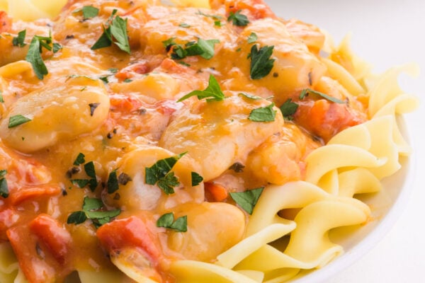 A serving of marry me butter beans over noodles on a plate.