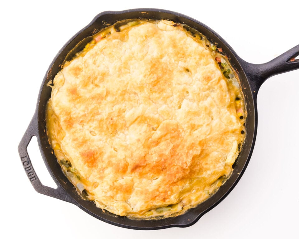 A golden pastry tops a pot pie in a black skillet.