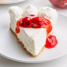 A slice of vegan no-bake cheesecake has cherry sauce on top.