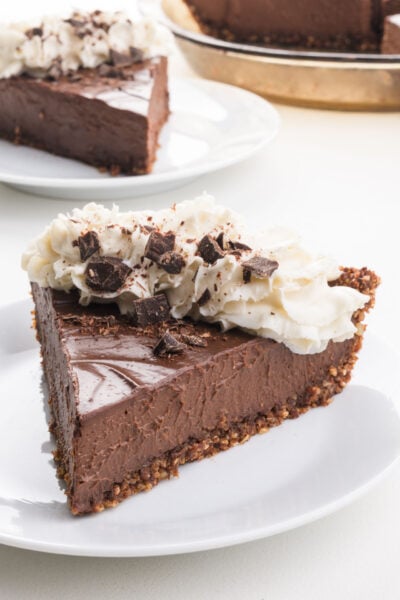 A slice of dairy-free chocolate pie on a plate with whipped cream on top.