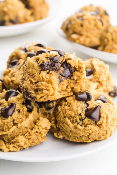 A bunch of tender, chewy chickpea cookies on a plate show lots of gooey, melty chocolate chips.
