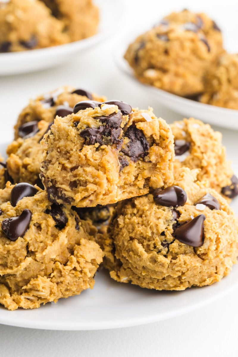 A bunch of tender, chewy chickpea cookies on a plate show lots of gooey, melty chocolate chips.