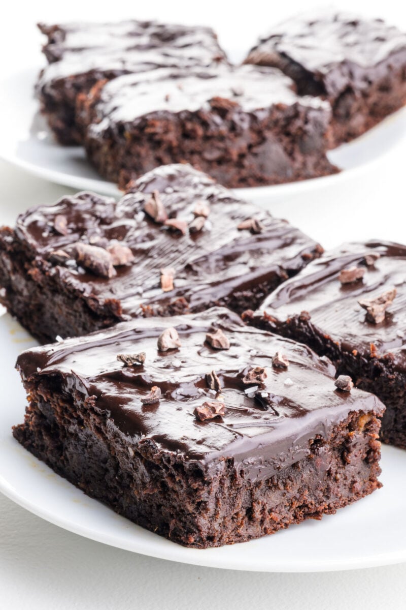 A plateful of decadent date brownies with shiny chocolate frosting on top.