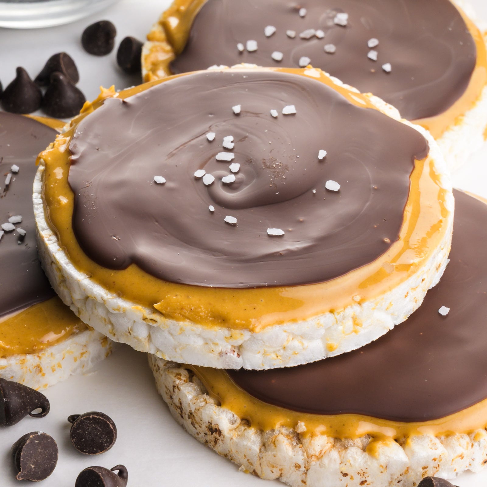 Several chocolate-topped peanut butter rice cakes on a white table.