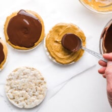 Chocolate sauce is being spread over a rice cake topped with peanut butter.